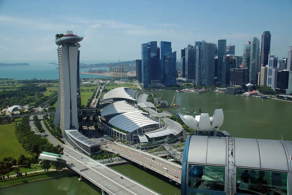 A view from the top of the Singapore Flyer over Marina Bay Sands, the lotus-shaped ArtScience Museum and the downtown towers, with the roof of another capsule at the edge of the frame